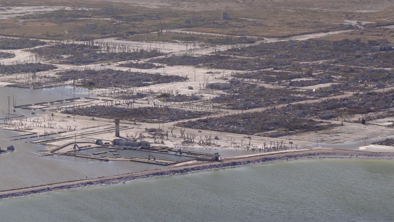 Salt-caked ruins, jetty, and grid streets line Epecuén’s ghostly shore at Villa Epecuén, Argentina, in this detailed drone shot, contrasting dark waters of the lake and the ochre pampas beyond