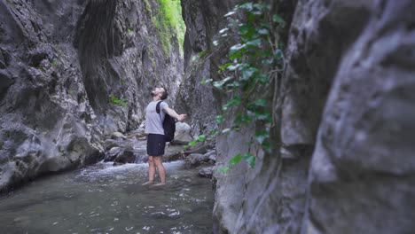 young man standing by stream in amazing nature.