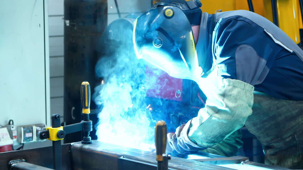 Repairman or technician worker working wearing industrial uniforms, Welded Iron Mask at Steel welding plants with sparks flying, industrial safety first concept.