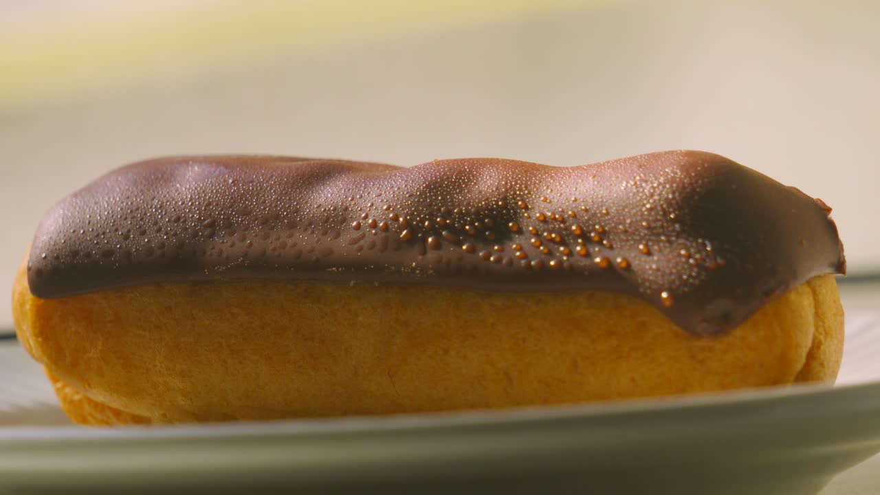 Slow Zoom into Eclair Topped with Smooth Milk Chocolate with Puff Pastry Filled with Fresh Whipped Cream. Traditional French Dessert Ready to Eat and Enjoy. Food Photography.