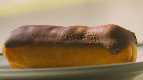 slow zoom into eclair topped with smooth milk chocolate with puff pastry filled with fresh whipped cream. traditional french dessert ready to eat and enjoy. food photography.