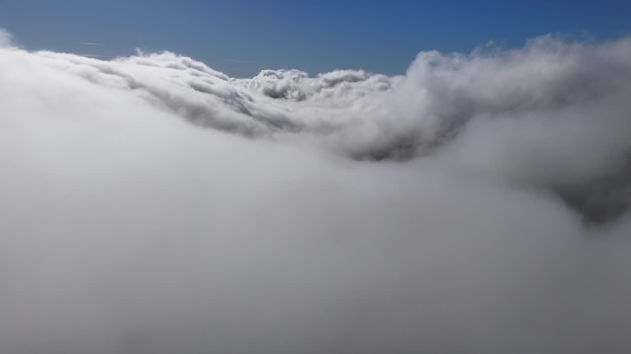 Drone reveal from inside the clouds on a sunny day with blue sky