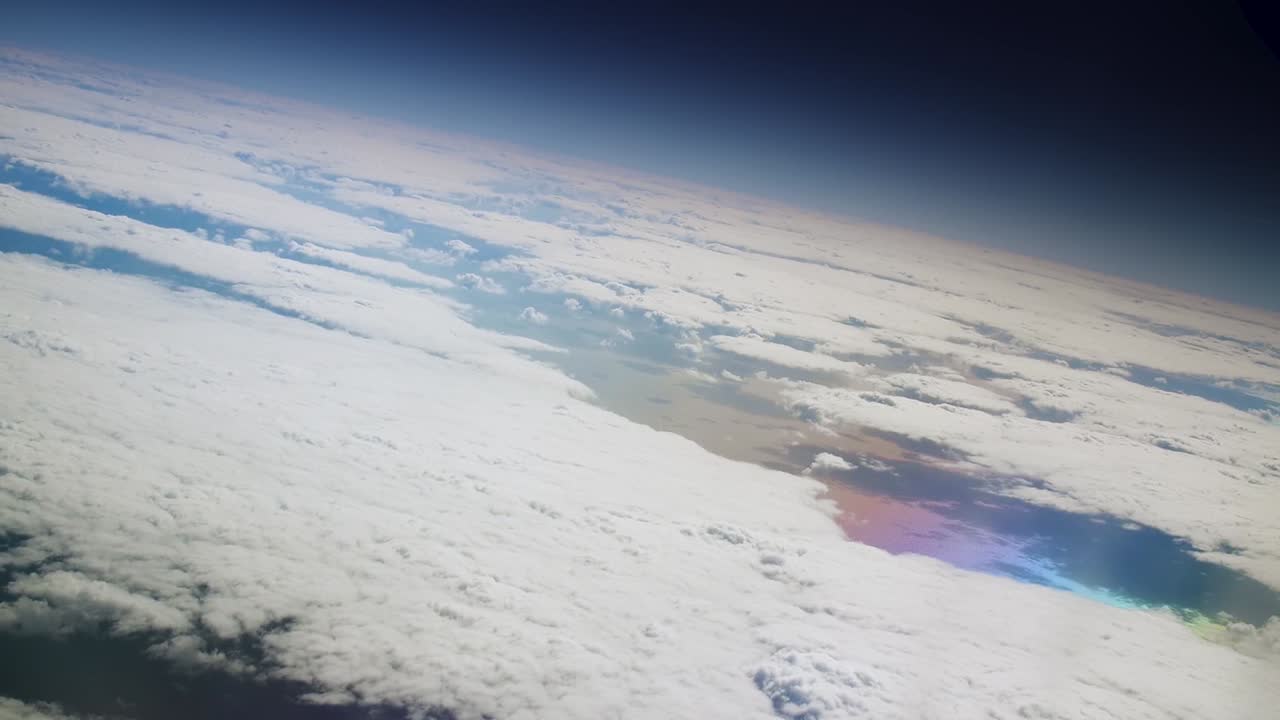 Earth curvature with black space and a colorful abstract ocean with the rainbown colors reflected under the clouds