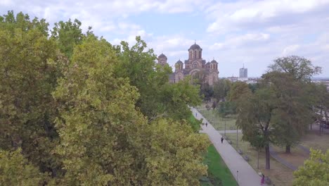 Slow-beautiful-opening-aerial-shot-of-Tasmajdan-Park-and-St-Marko-church-with-trees