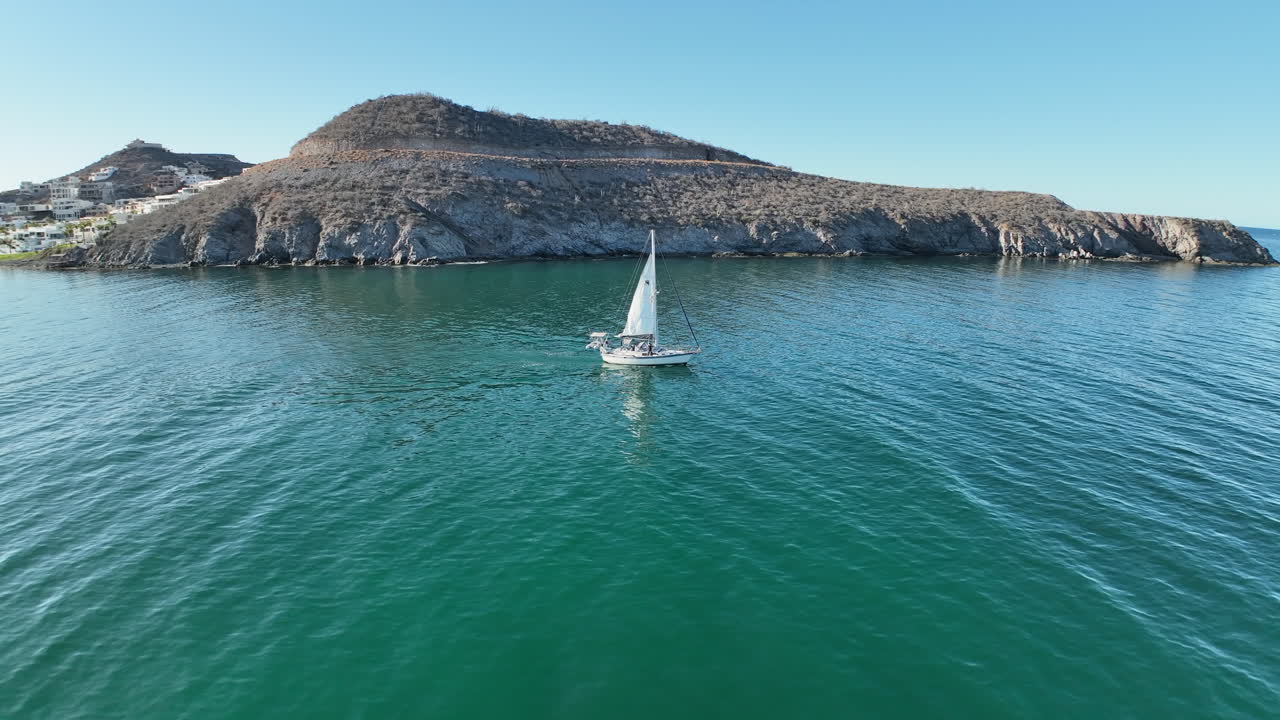Circular aerial shot of a sailboat leaving the marina