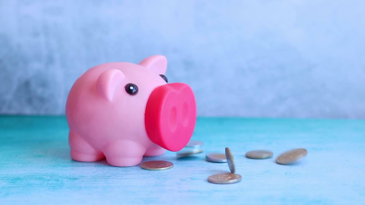 Coins Falling Next to a Pink Piggy Bank