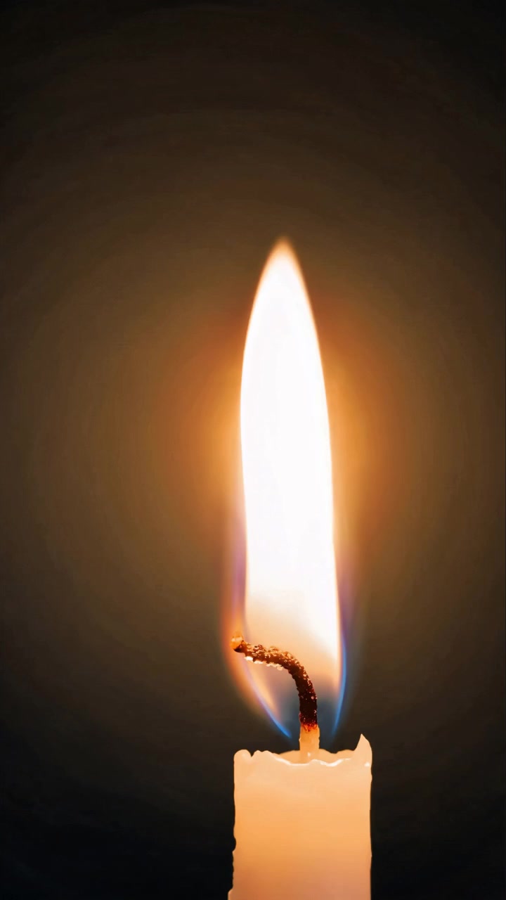 Fiamma di candela bianca che tremola dolcemente su uno sfondo scuro.