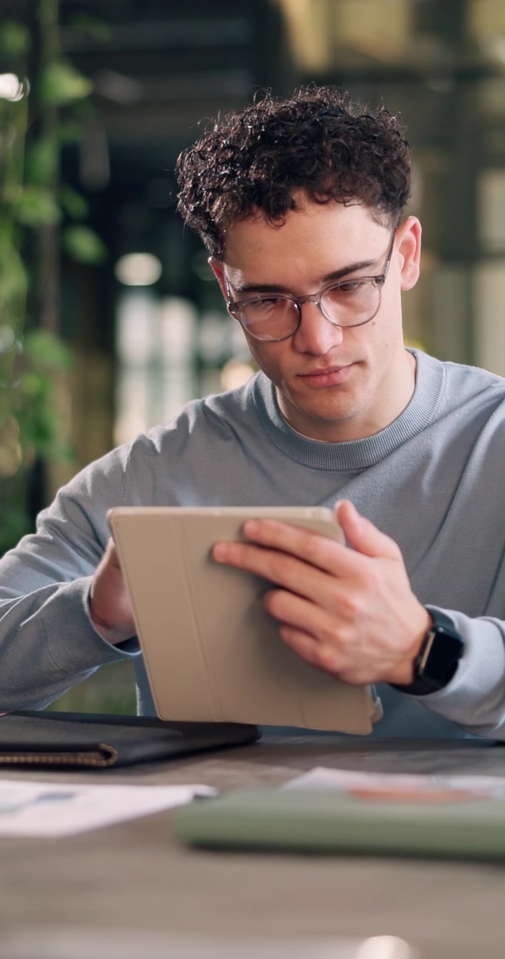 Ung mand bruger digital tablet på moderne kontorarbejdsplads