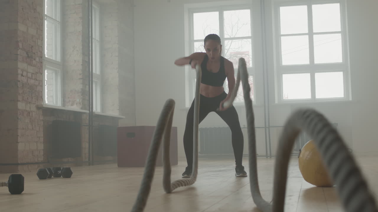 Strong Woman With Battle Rope In Gym