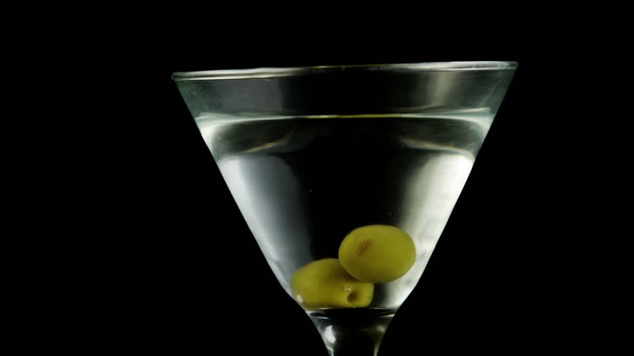 un vaso de cóctel con aceitunas verdes