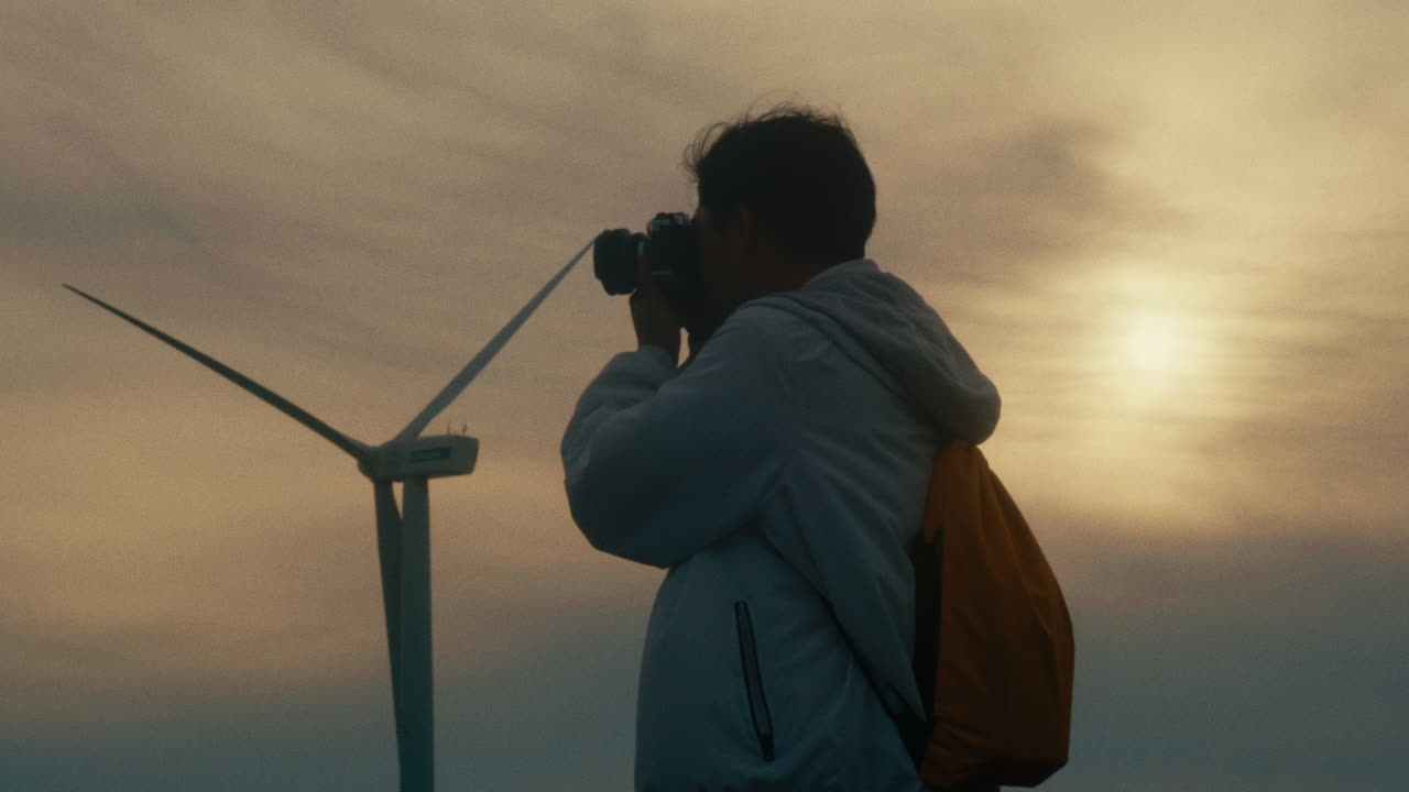 Photographer capturing sunset over wind turbines