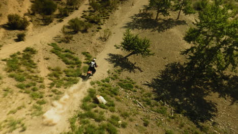 motorbiker rides vehicle along ground road fpv drone. extreme sportsman on motorcycle enjoys trip across hilly valley. racing competition offroad