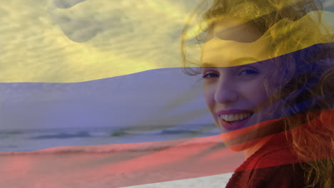 composite video of waving columbia flag over portrait of caucasian woman smiling at the beach