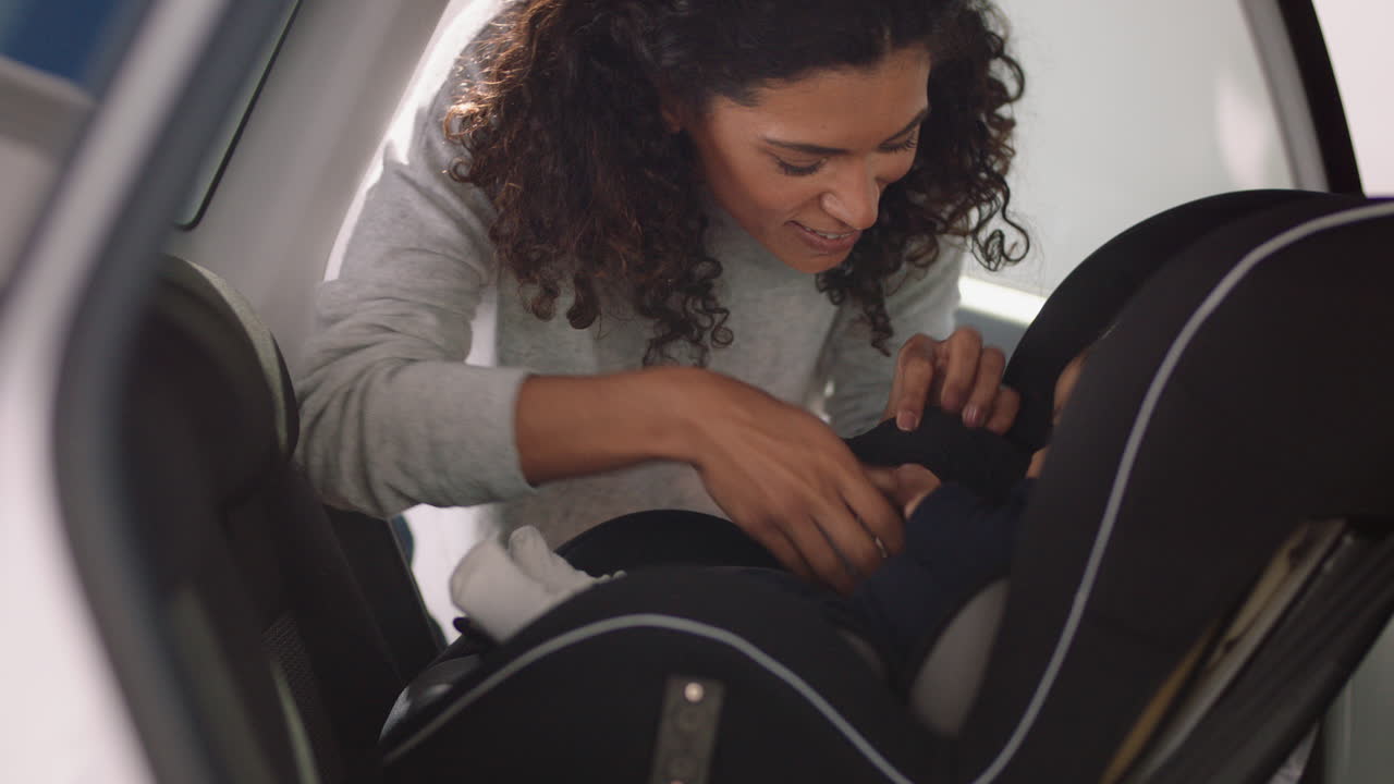 madre joven poniendo al bebé en el asiento del coche asegurando al niño para el viaje por carretera padre responsable cuidando de los niños pequeños seguridad en el vehículo