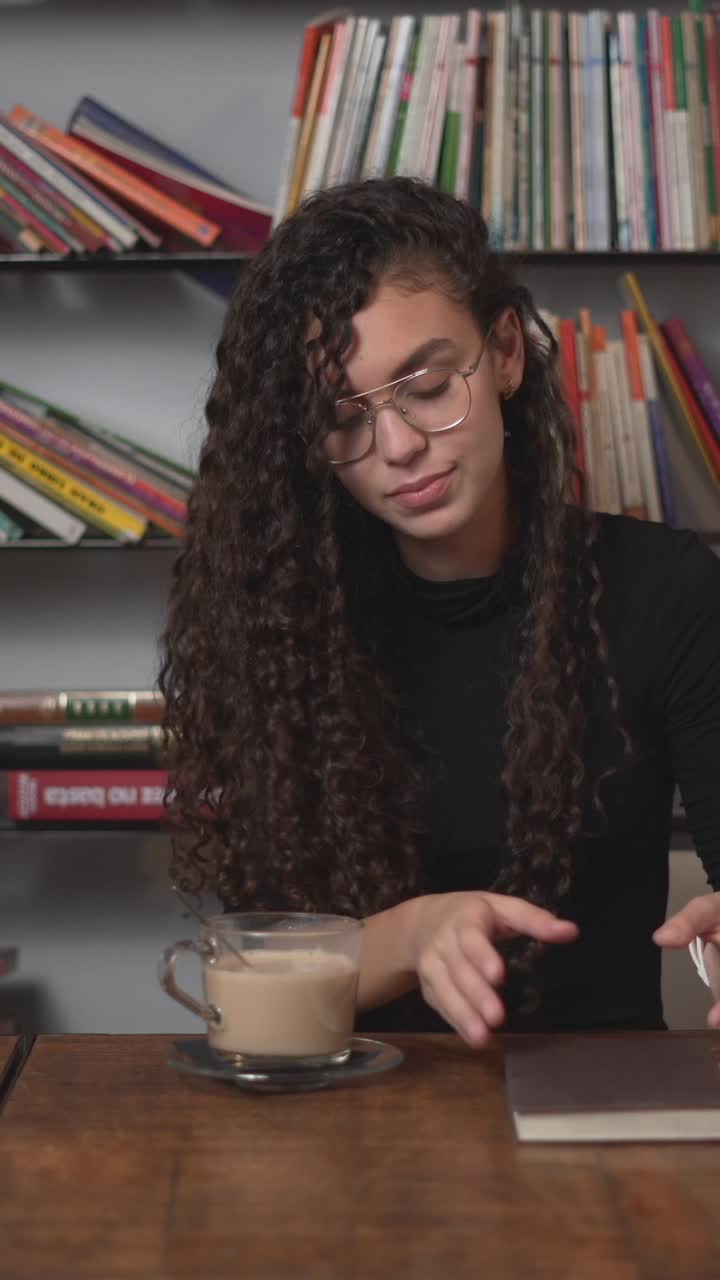 Young Woman Reading and Drinking Coffee in a Cafe