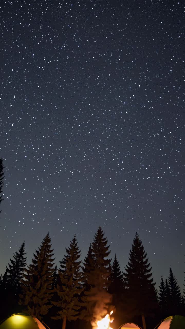 A mesmerizing night sky full of stars above a campsite with tents and a fire