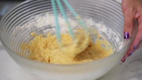 female hands mixing dough in the kitchen using whisk. homemade food. slow motion shot