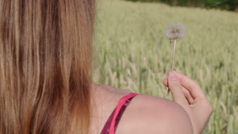 Una-Mujer-Que-Sopla-Un-Diente-De-León-Afuera-En-El-Verde