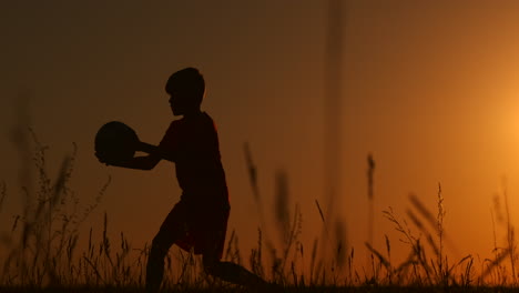 Ein-Junger-Fußballspieler-Trainiert-Mit-Einem-Ball,-Der-An-Seinem-Bein-Hängt,-Bei-Sonnenuntergang-In-Zeitlupe-Während-Der-Goldenen-Stunde-Auf-Dem-Feld-Bis-Zum-Sonnenuntergang.-Training-Von-Der-Dämmerung-Bis-Zum-Morgengrauen.-Konzeptweg-Zum-Erfolg