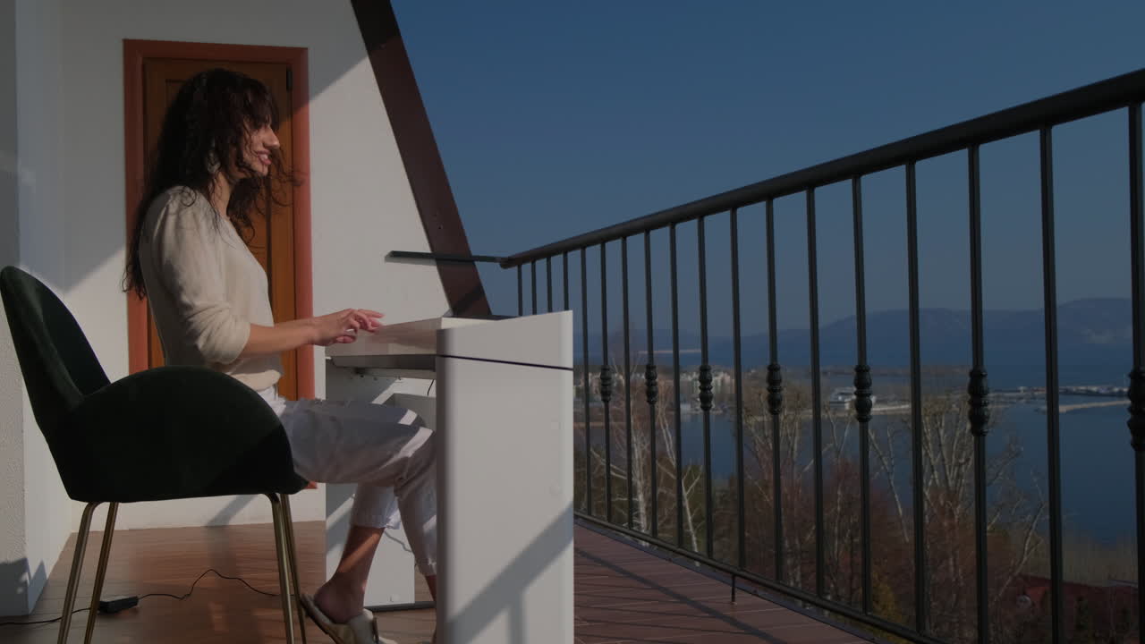 mujer trabajando en un balcón con vistas al lago