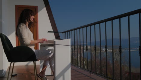 Woman working on a balcony with a lake view
