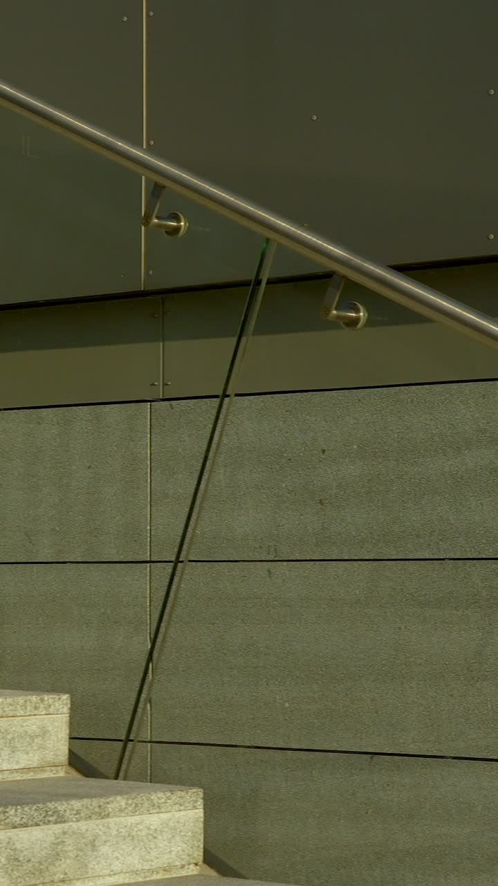 Plano vertical de escadas exteriores minimalistas com painéis de vidro e corrimãos de metal. Ideal para conteúdo de design arquitetónico e desenvolvimento urbano.