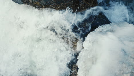 fuerte flujo de agua en el río congelado entre grandes piedras, cierre, cámara lenta
