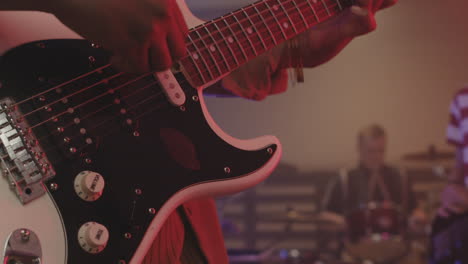 close up of an unrecognizable girl playing guitar during a band rehearsal in recording studio