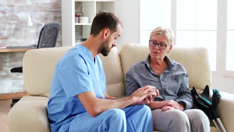 male doctor assistant sitting on the couch with senior woman