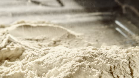 close up of wheat flour scattered onto pile in the process of baking bread