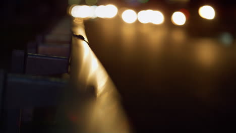 Night-highway-guardrail-reflecting-car-beams-closeup.-Evening-traffic-lights