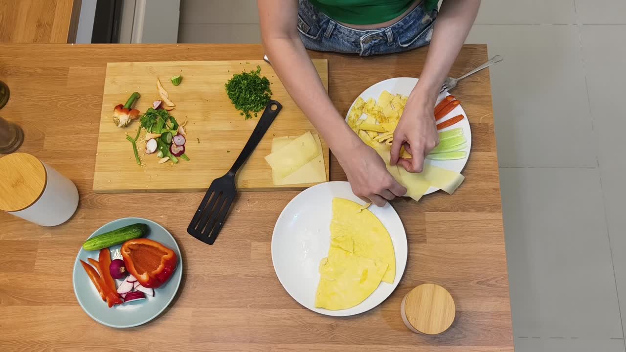 Woman preparing a healthy breakfast with omelet and fresh vegetables