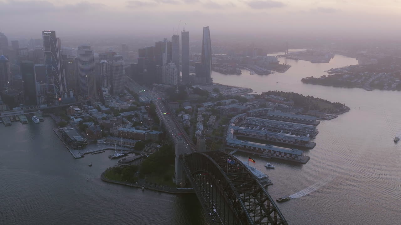 Aerial view over Harbour Bridge and away from the Sydney skyline, hazy dusk