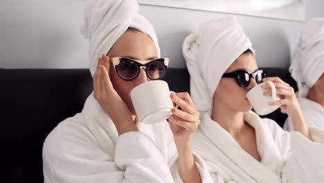 caucasian girls drinking coffee and relaxing in hotel room.