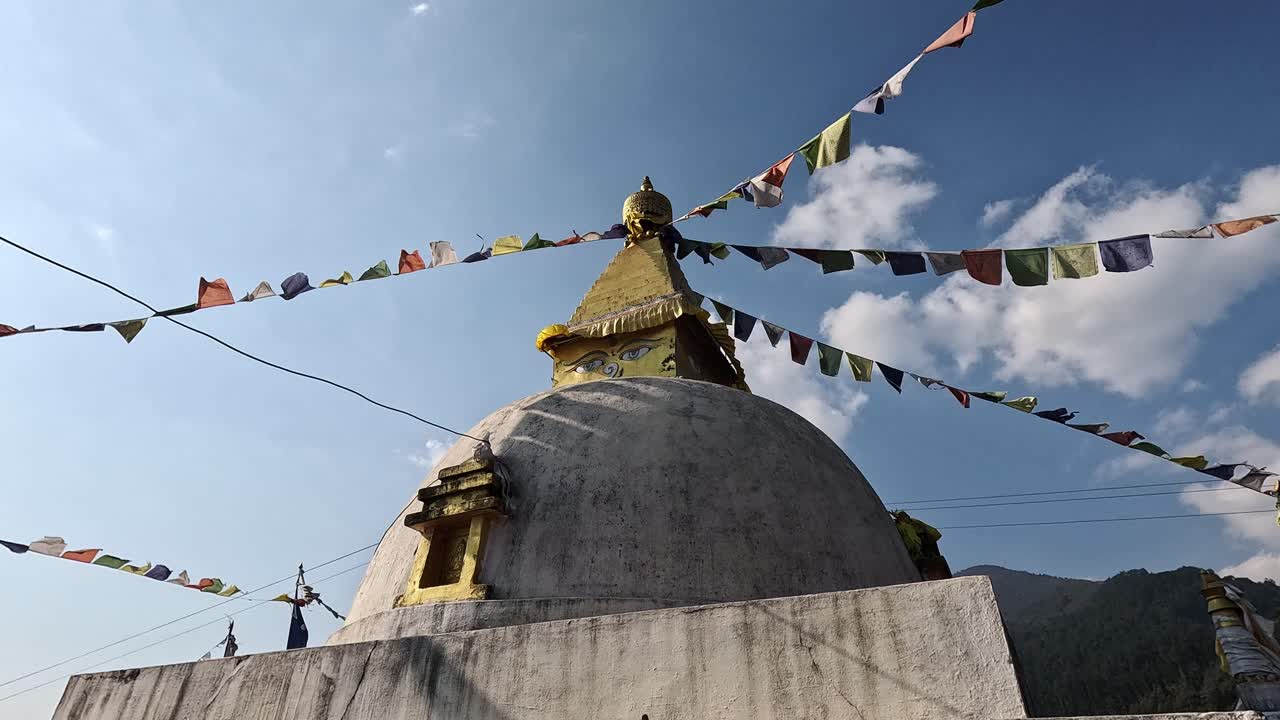 Close up of white stupa with face and colorful prayer flags flattering in the wind