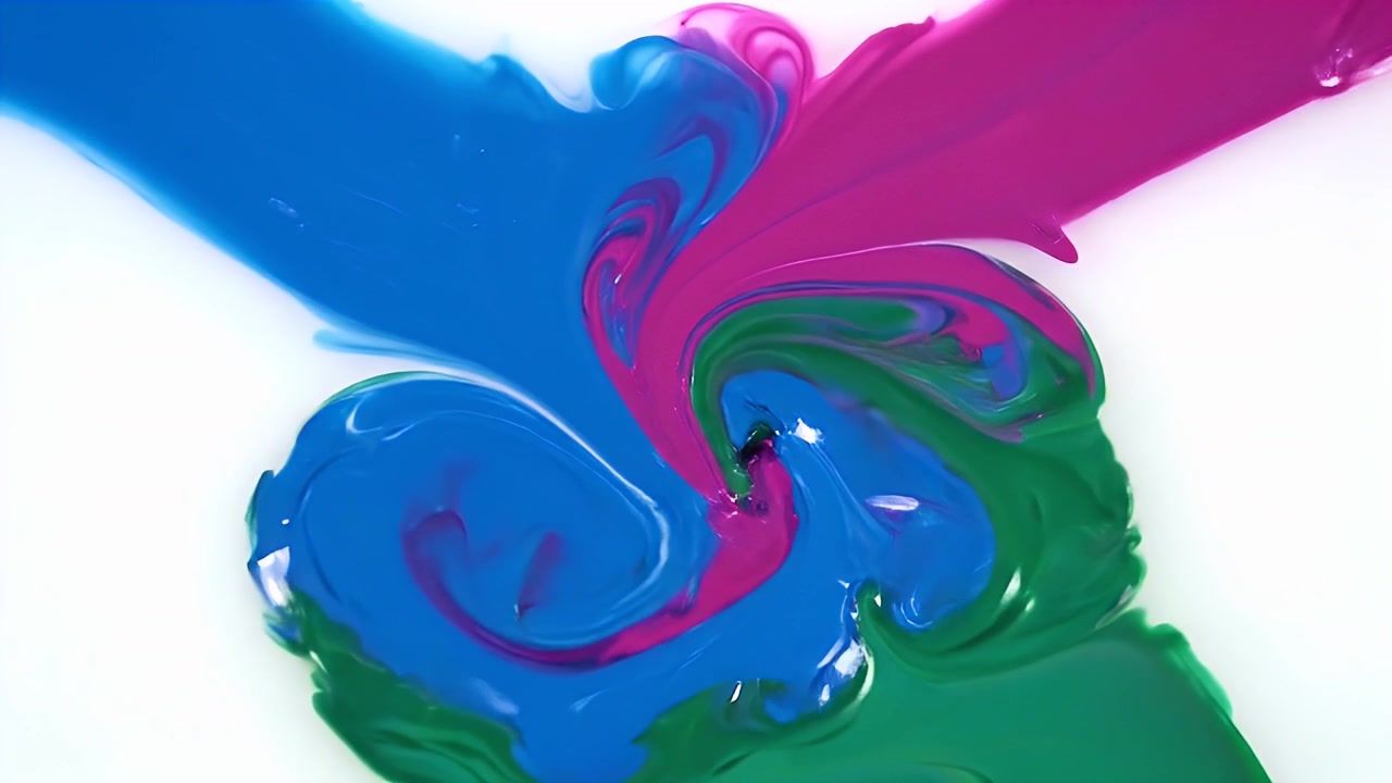Pintura azul, magenta y verde mezclándose sobre una superficie blanca