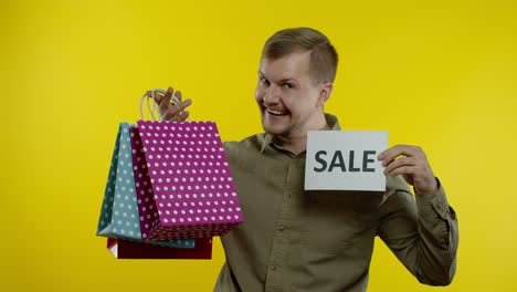Fröhlicher-Lächelnder-Mann-Mit-Einkaufstüten,-Der-Die-Aufschrift-„Black-Friday“-Auf-Den-Taschen-Und-Eine-Verkaufsnotiz-Zeigt