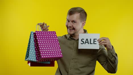 Happy-smiling-man-with-shopping-bags-showing-Black-Friday-inscription-on-bags-and-Sale-word-note