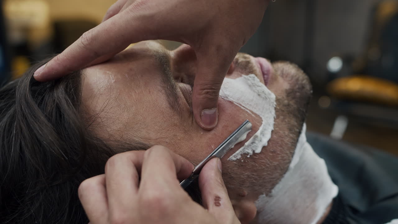 Mand får en tæt barbering i en barbersalon