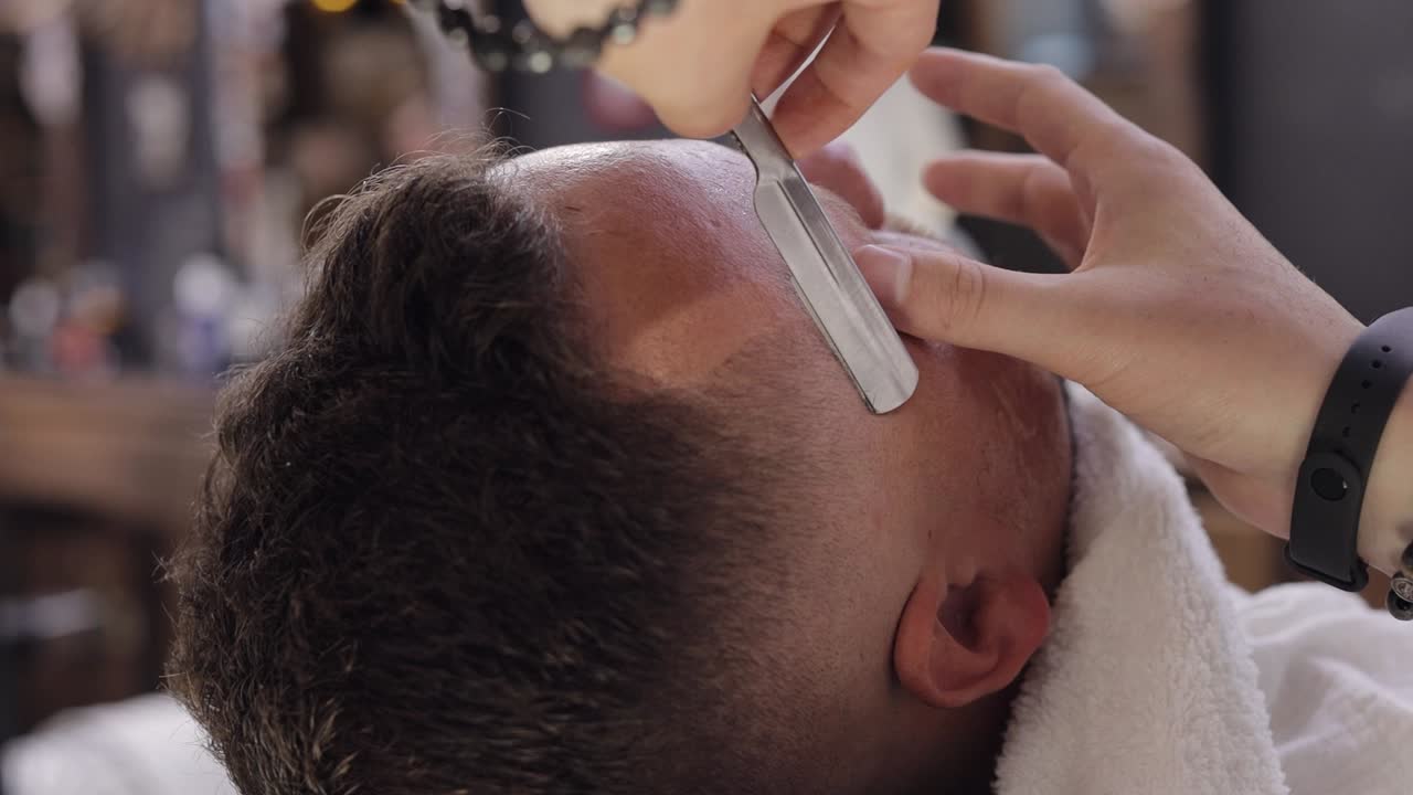 Barbiere che taglia i capelli con un rasoio a mano libera, il barbiere fa un taglio di capelli per il cliente sposo in barberia.