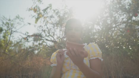 an attractive asian female carefully painting a clay pot enjoying her hobby as she sits outdoors with the morning sun shining through the trees on a beautiful day, india