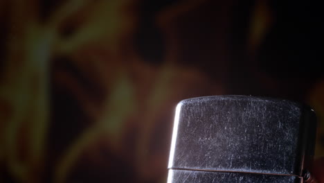 Turning-off-burning-steel-lighter-with-flames-in-background,-close-up-view