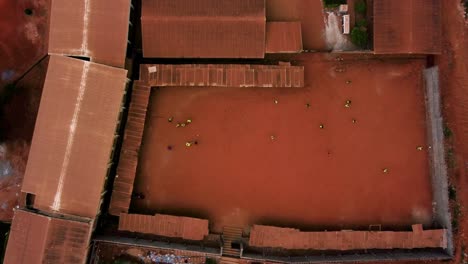 people playing street soccer on a red sand field in a african city- cenital, aerial view