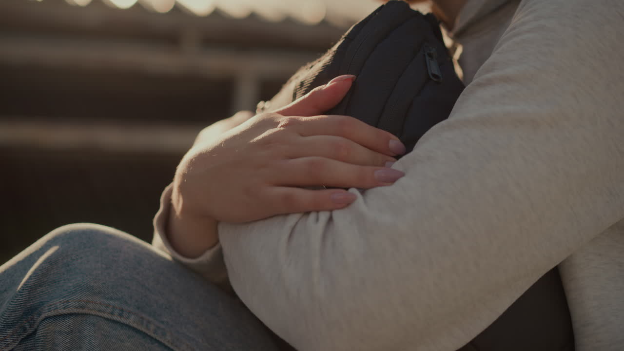 잘 은 손을 가진 개인의 손이 가게 가에 반사되는 것처럼 가방을 단단히 포옹하는 클로즈업, 따뜻하고 상적인 분위기를 만니다.