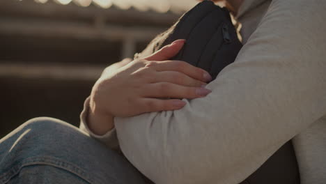 primer plano de las manos de individuos con uñas bien pulidas abrazando fuertemente una bolsa mientras la luz del sol se refleja suavemente en su piel, creando una atmósfera cálida y contemplativa