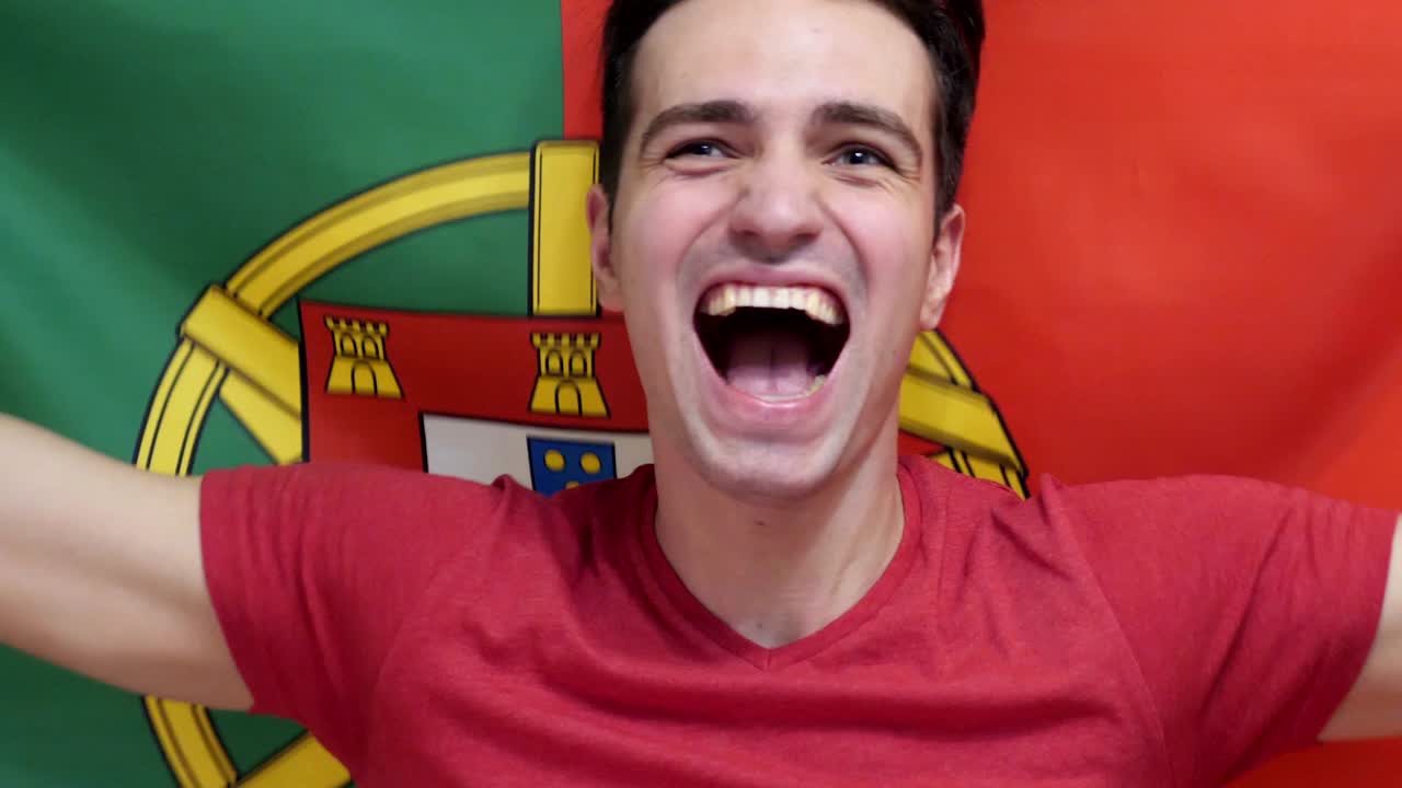 joven portugués celebra sosteniendo la bandera de portugal en cámara lenta