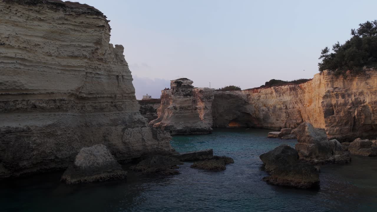 Sea stacks and arches at Torre Sant'Andrea, Puglia, limestone cliffs, and beautiful coastline at dusk, Italy. Aerial drone at low altitude