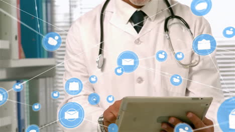 animation of email and message network over happy caucasian male doctor using tablet