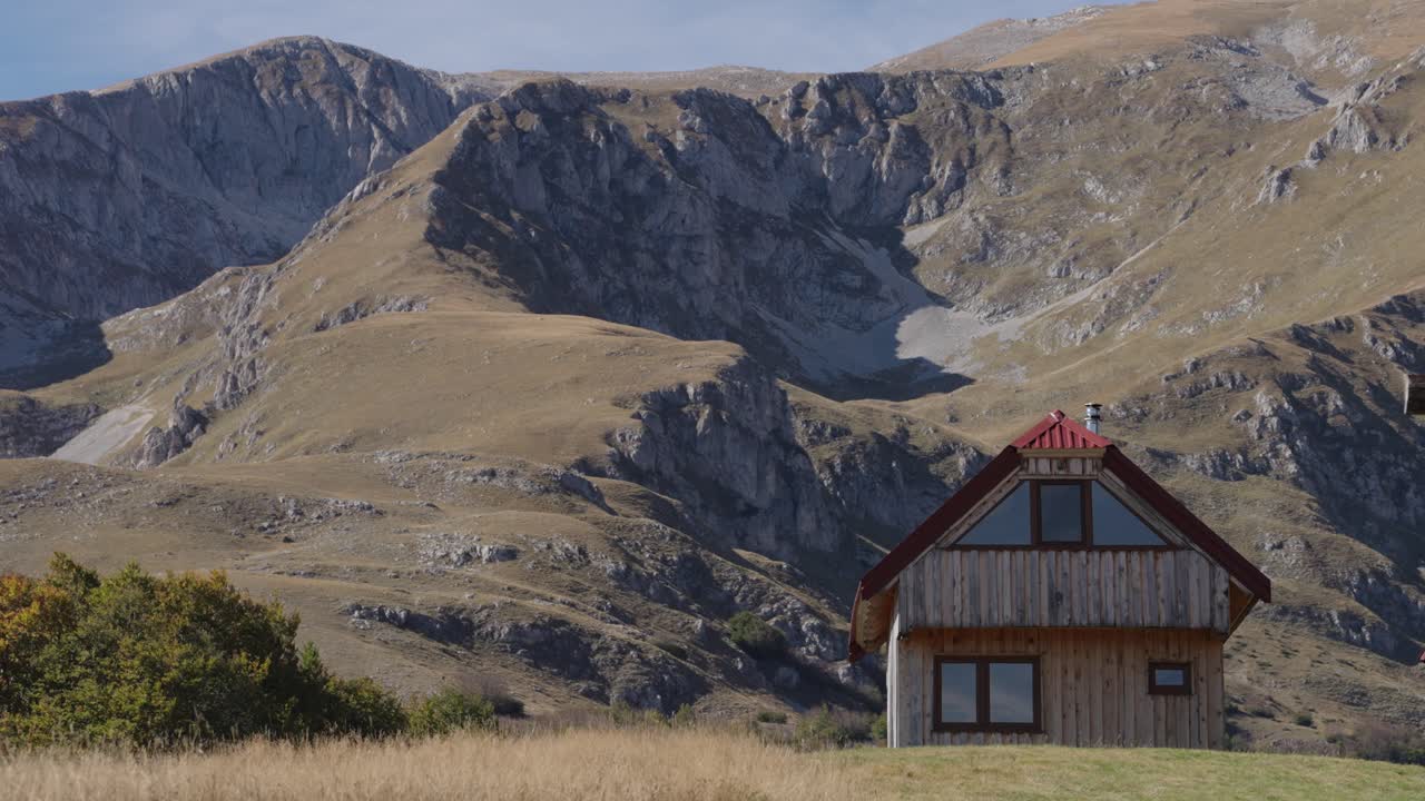 A cozy house stands before towering mountains in Durmitor, surrounded by stunning nature