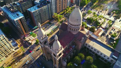 aerial establishing shot of latin american catholic basilica, streets of chile santiago city during daylight traffic around trees